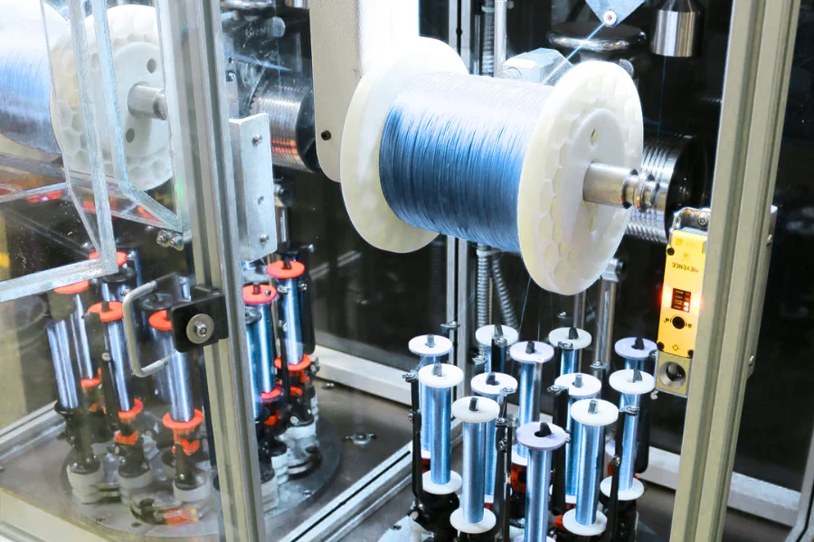Multifilament braiding system for PGA surgical sutures showing controlled tension and precision weaving process